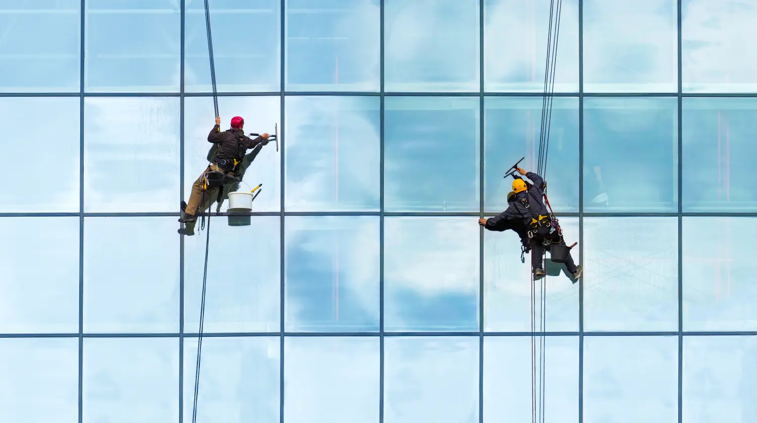 Gruppe von Arbeitern Reinigung von Fenstern Service auf Hochhaus. Arbeiter reinigen Glasfassade. Spezielles Job-Konzept